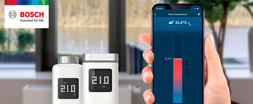 Bosch Smart Home radiatortermostat II med display på 21°C styrs via Bosch Smart Home-app på smartphone