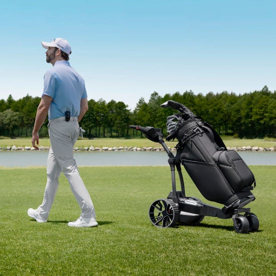 Golfspelare går bredvid Navee elektrisk golfvagn med golfbag på golfbanan