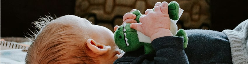 Babypojke med gosedjur i händerna, presentidé till pojkar som inbjuder till lek och trygghet.