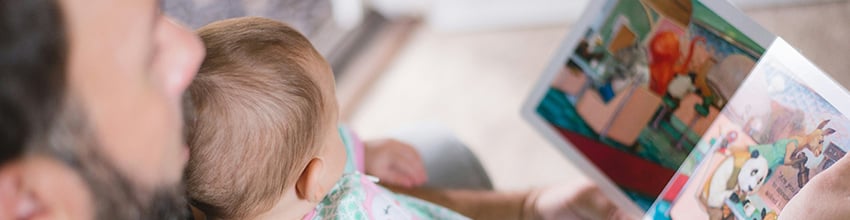 Pappa med baby i knät läser högt, presentidé som stärker närhet och tid tillsammans för nyblivna pappor.