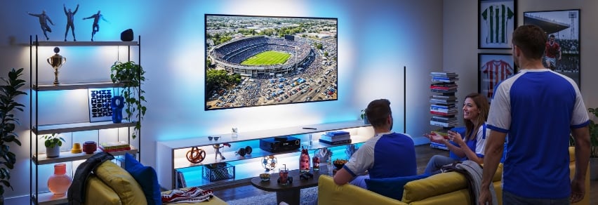 Vänner reagerar på rött kort på TV med dramatisk röd WiZ Sports Live-belysning i vardagsrummet