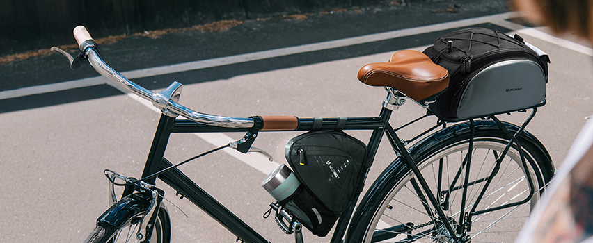 Vintage-cykel med Wozinsky sadel- och ramväska parkerad på solig gata – cykeltillbehör för turister