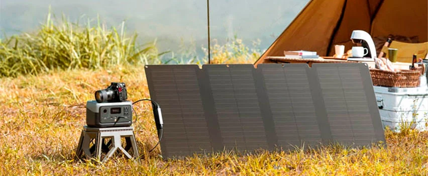 EcoFlow RIVER 2 powerstation och solpanel uppställd vid tält på äng – kompakt off-grid energilösning för camping